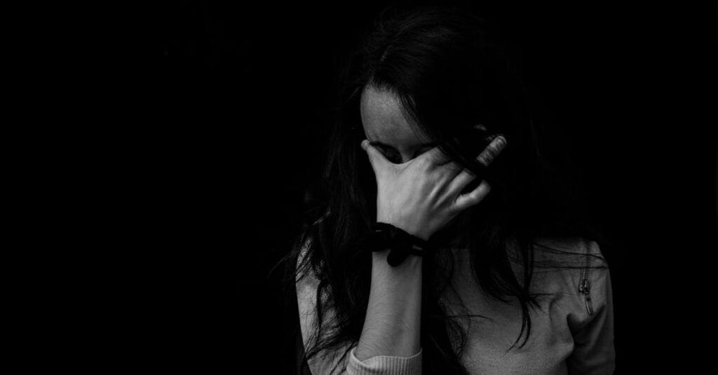 Intense black and white portrait capturing the emotion and introspection of a woman covering her face.